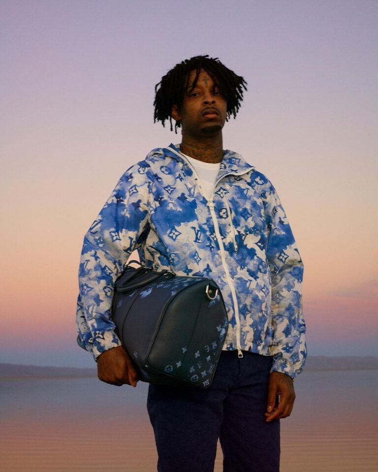 Camisa azul estampada com bolsa transversal e calça escura em um retrato ao entardecer.