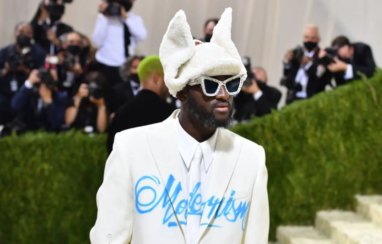 Virgil Abloh com roupa branca, óculos e uma máscara erguida sobre a cabeça.