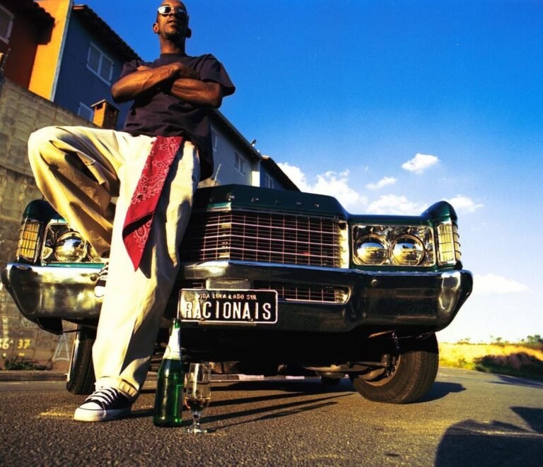 Look de streetwear com calça larga em uma imagem dos Racionais MC’s junto a um carro.