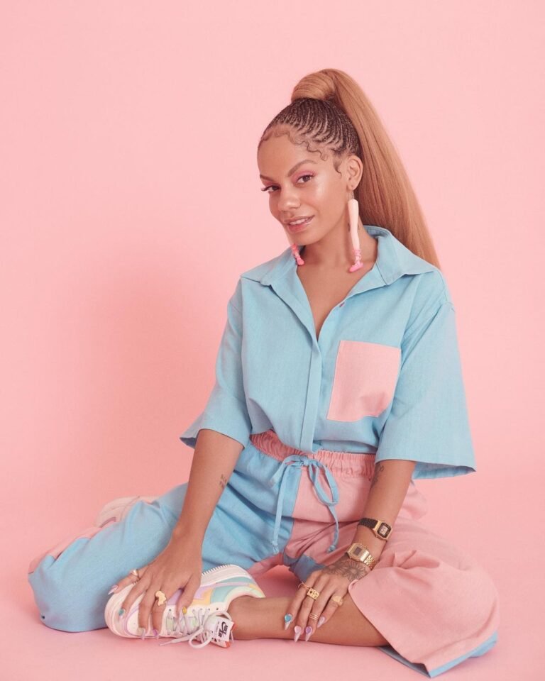 Conjunto azul-claro e rosa com camisa de manga curta e saia, diante de um fundo rosa.