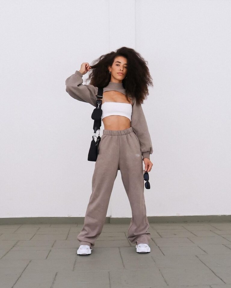 Conjunto de calça e jaqueta cinza com top branco e tênis.