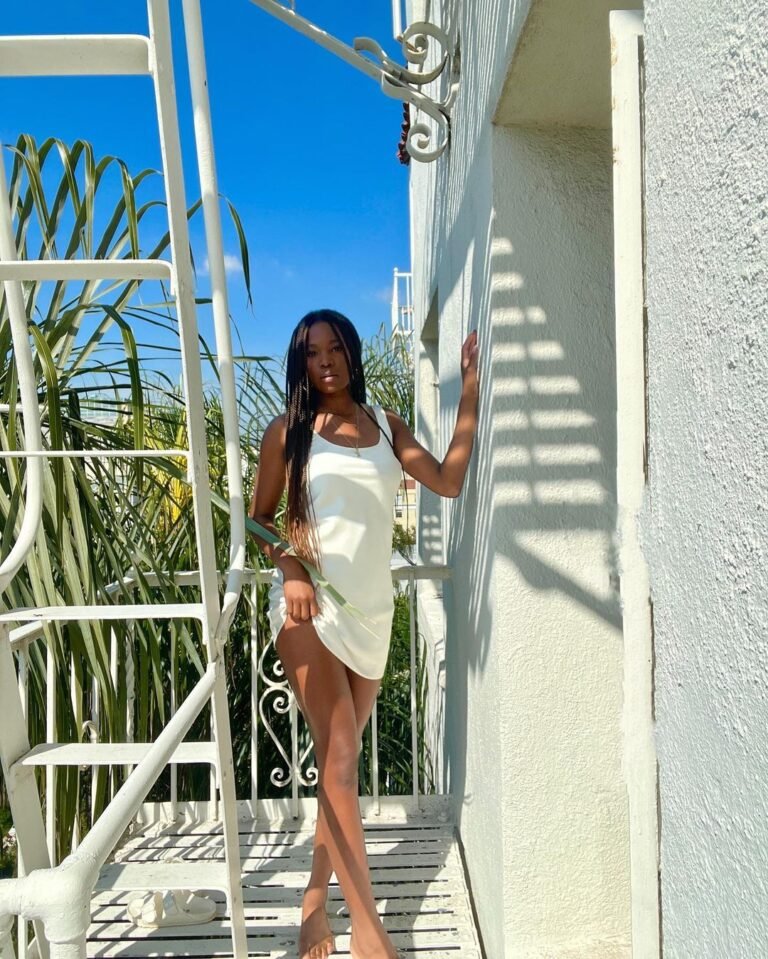 Vestido curto claro com recortes laterais, fotografado ao lado de uma escada.