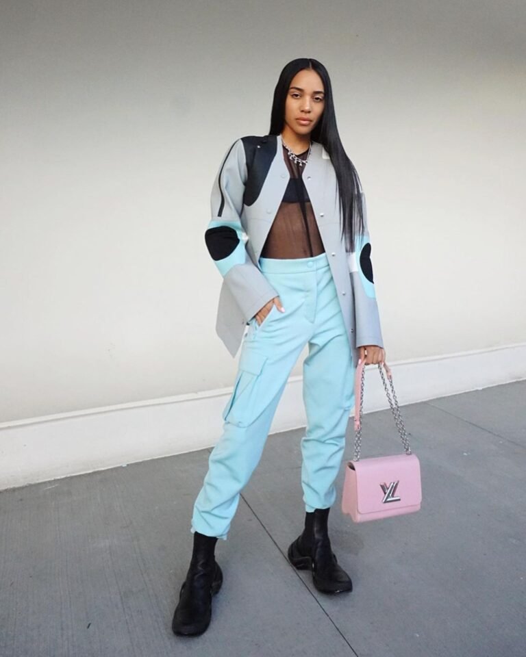 Blazer e calça azul-claros com top preto, botas e bolsa rosa.