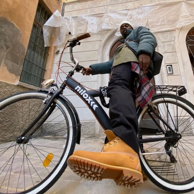 Pessoa com bicicleta e botas Timberland amarelas em primeiro plano.