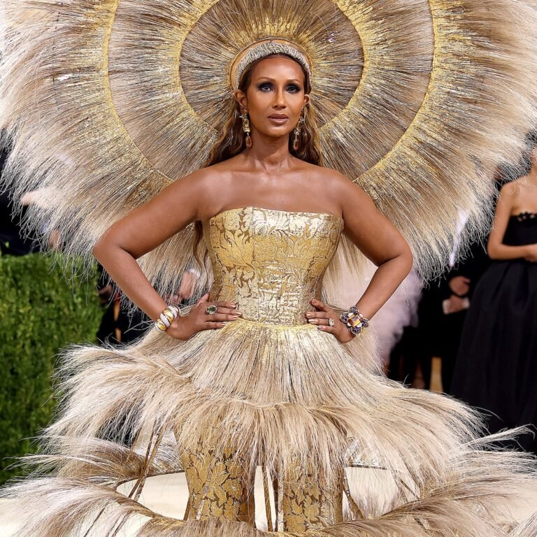 Vestido dourado de franjas com um grande adorno circular na cabeça, no Met Gala 2021.