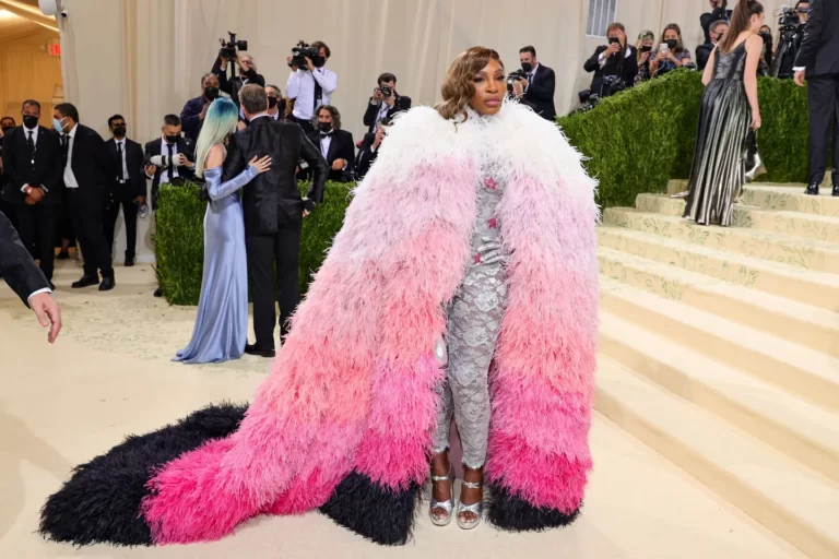 Capa de plumas em rosa, branco e preto sobre um vestido brilhante no Met Gala 2021.