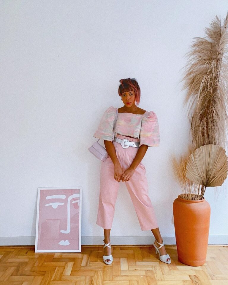 Calça rosa de cintura alta com camisa curta e sandálias claras.