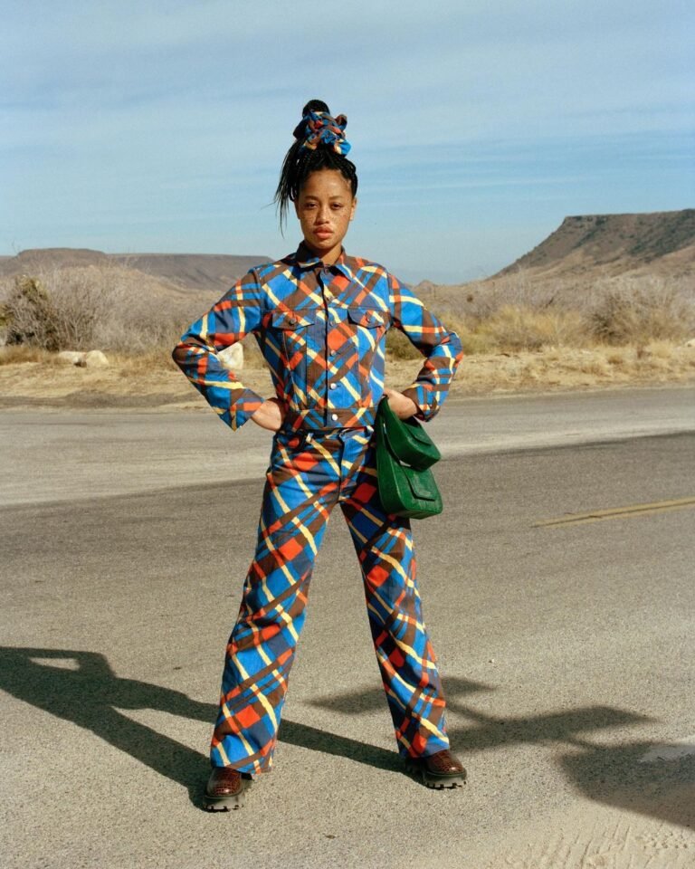 Conjunto de calça e blazer com estampa geométrica colorida em uma paisagem aberta.