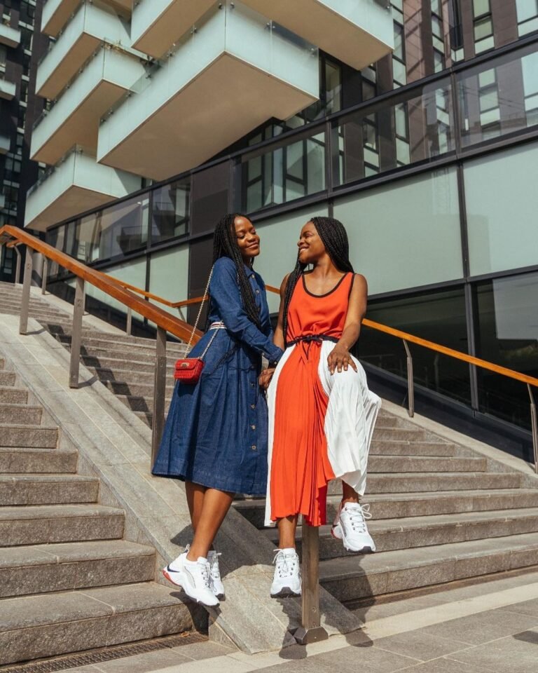 Dois looks com vestidos em azul e laranja, casacos e tênis, em uma escadaria.