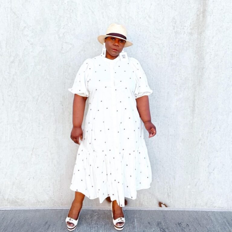 Vestido branco midi com chapéu e tênis em um look monocromático.