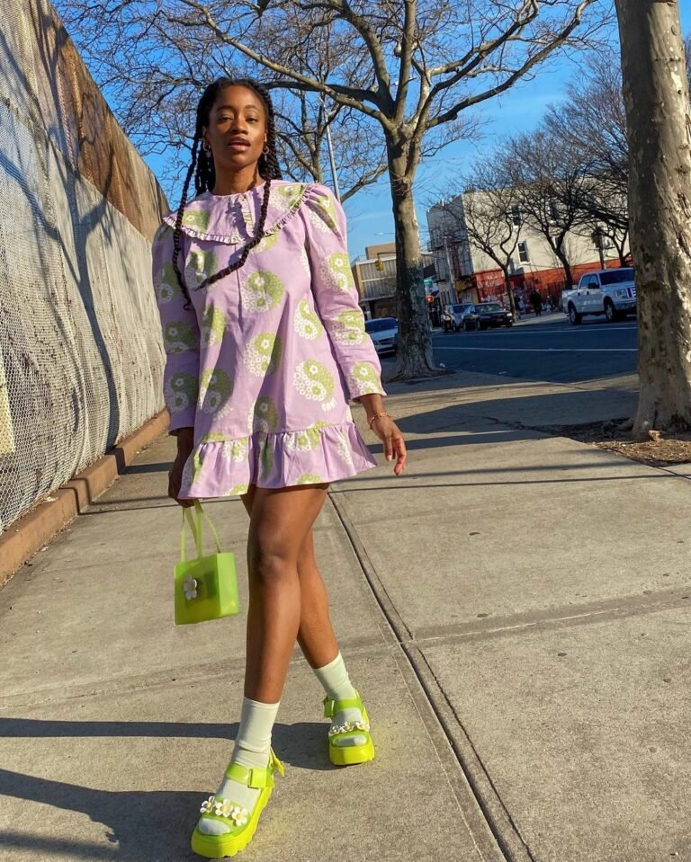 Vestido estampado em tons claros com sapatos e bolsa verdes.