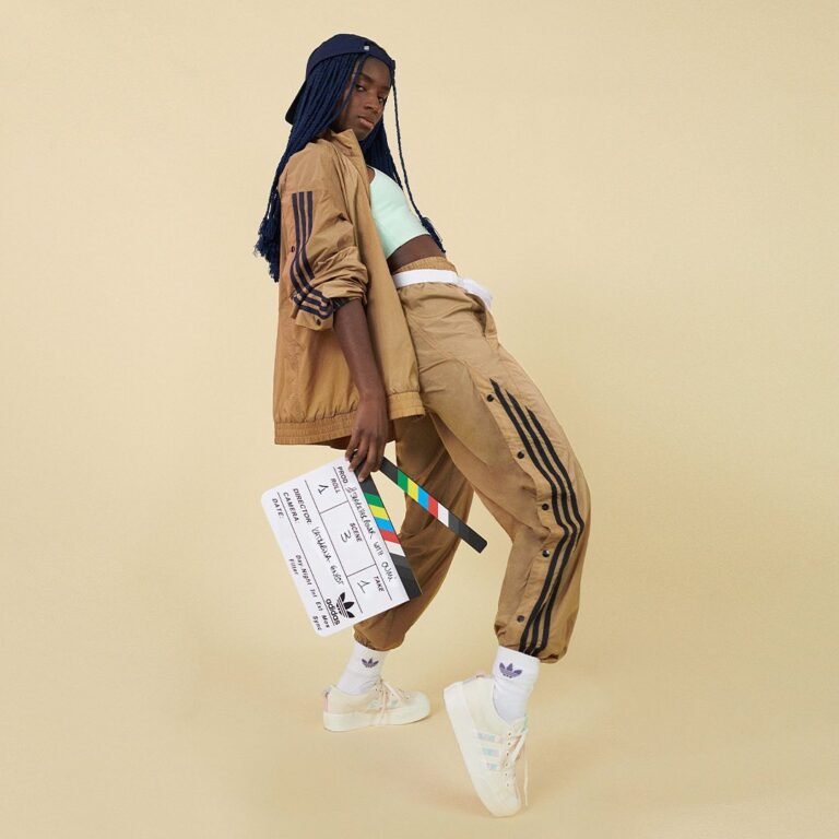Conjunto esportivo marrom com listras laterais e botas brancas de salto.