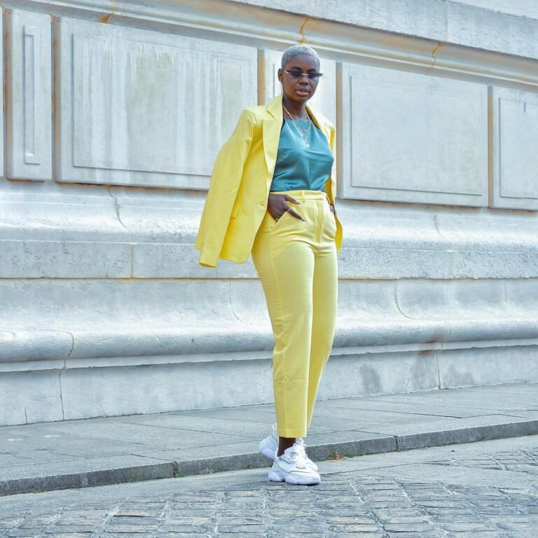 Terno amarelo com top azul e tênis brancos em uma fotografia ao ar livre.