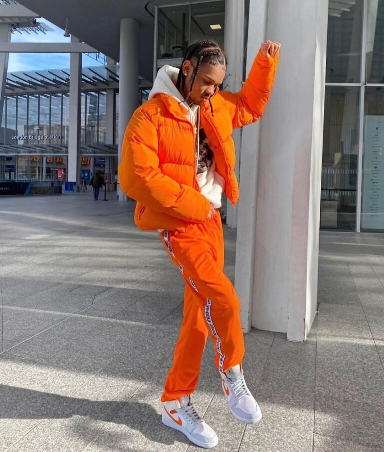 Jaqueta puffer laranja com calça e tênis na mesma paleta.