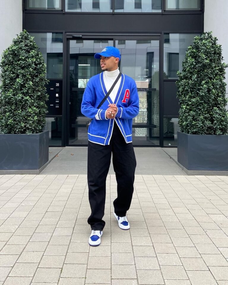 Jaqueta esportiva azul com calça preta, boné e tênis azuis.
