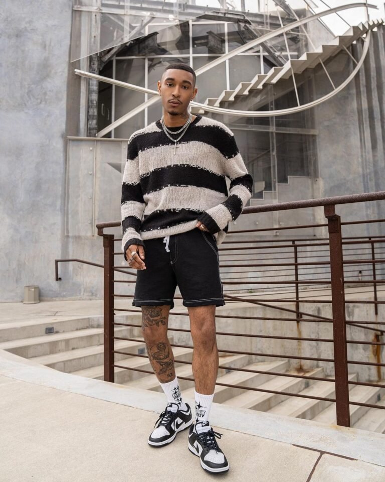 Suéter listrado em preto e branco com shorts pretos e tênis de cano alto.