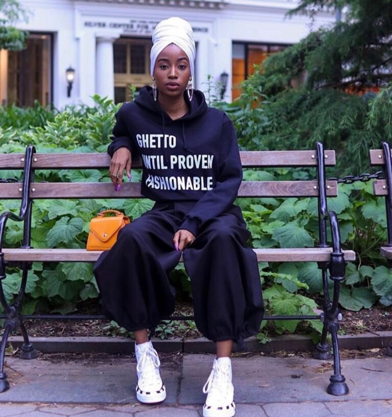 Moletom preto com a frase “Ghetto Until Proven Fashionable”, usado em um retrato sentado.