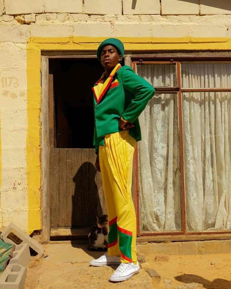 Sapeur de blazer verde e calça amarela diante de uma porta.