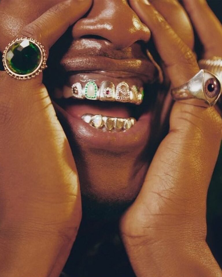 Close de grillz e anéis grandes com pedras coloridas.