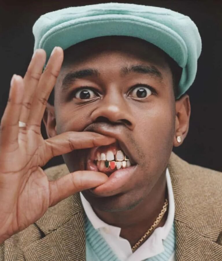 Pessoa de boné verde mostrando o grillz com os dedos.