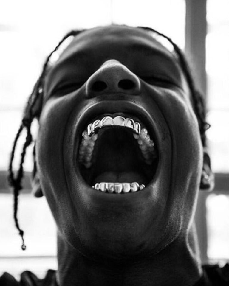 Sorriso com grillz em uma fotografia em preto e branco vista de baixo.