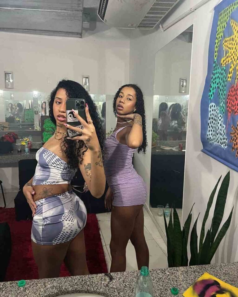 Tasha e Tracie mostram looks com tops e peças curtas em uma foto no espelho.