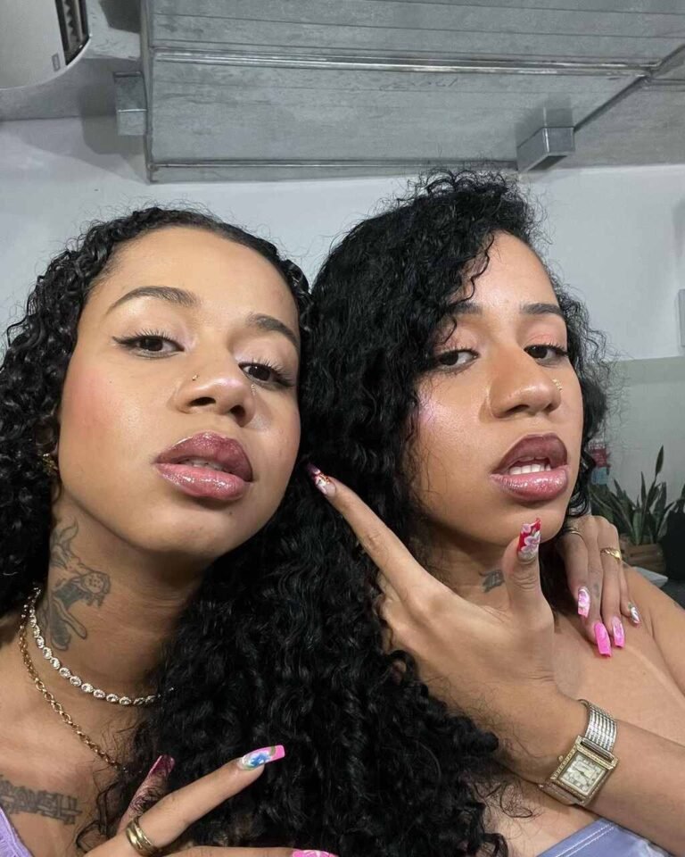 Tasha e Tracie em um retrato com tops e cabelos soltos.